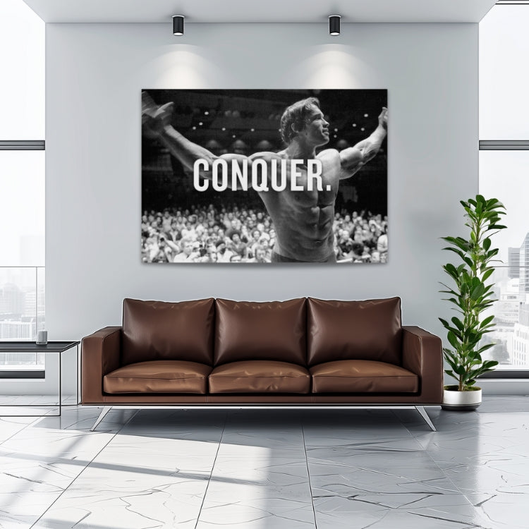 Motivační obraz s Arnoldem Schwarzenegerem, kulturista s roztaženýma rukama a slovem CONQUER. Motivační obrazy.