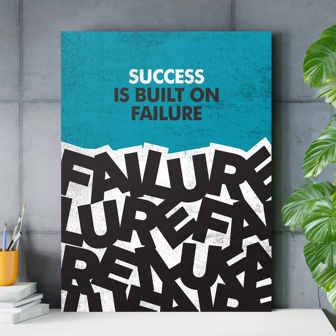 Motivační obraz - Success Is Built on Failure nad pracovním stolem.