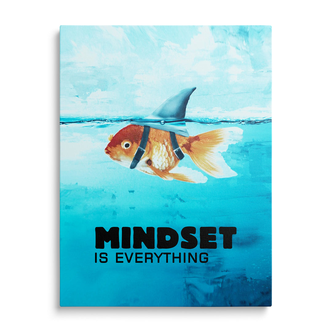 Oranžová zlatá rybka pod modrou hladinou s připevněnou žraločí ploutví a černým nápisem Mindset Is Everything dole.
