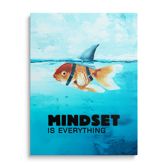 Oranžová zlatá rybka pod modrou hladinou s připevněnou žraločí ploutví a černým nápisem Mindset Is Everything dole.