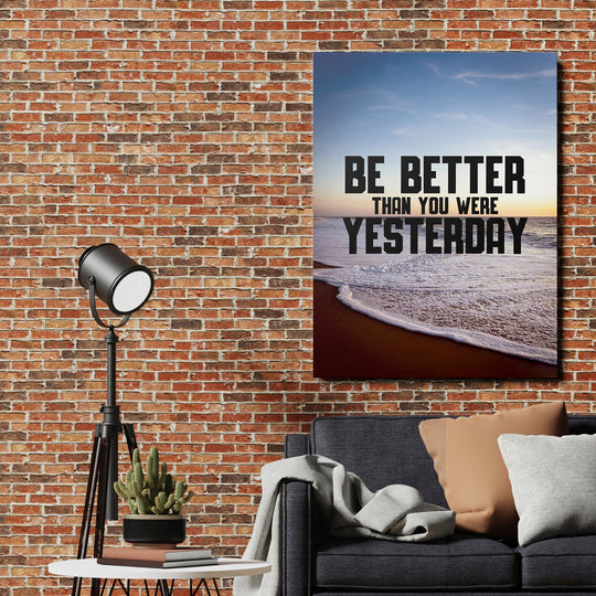 Motivační obraz - Be Better Than Yesterday na cihlové zdi.