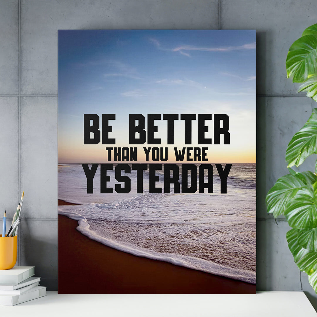 Motivační obraz - Be Better Than Yesterday nad pracovním stolem.