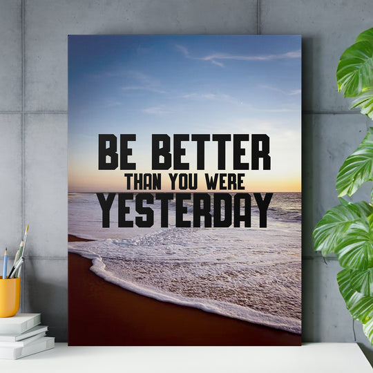 Motivační obraz - Be Better Than Yesterday nad pracovním stolem.