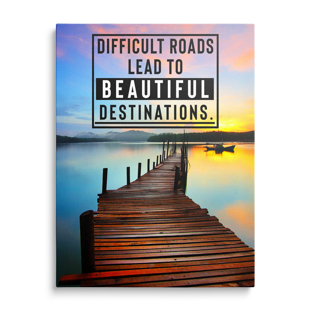 Dřevěné molo v klidném jezeře při růžovooranžovém západu slunce a rámeček s textem Difficult Roads Lead to Beautiful Destinations.