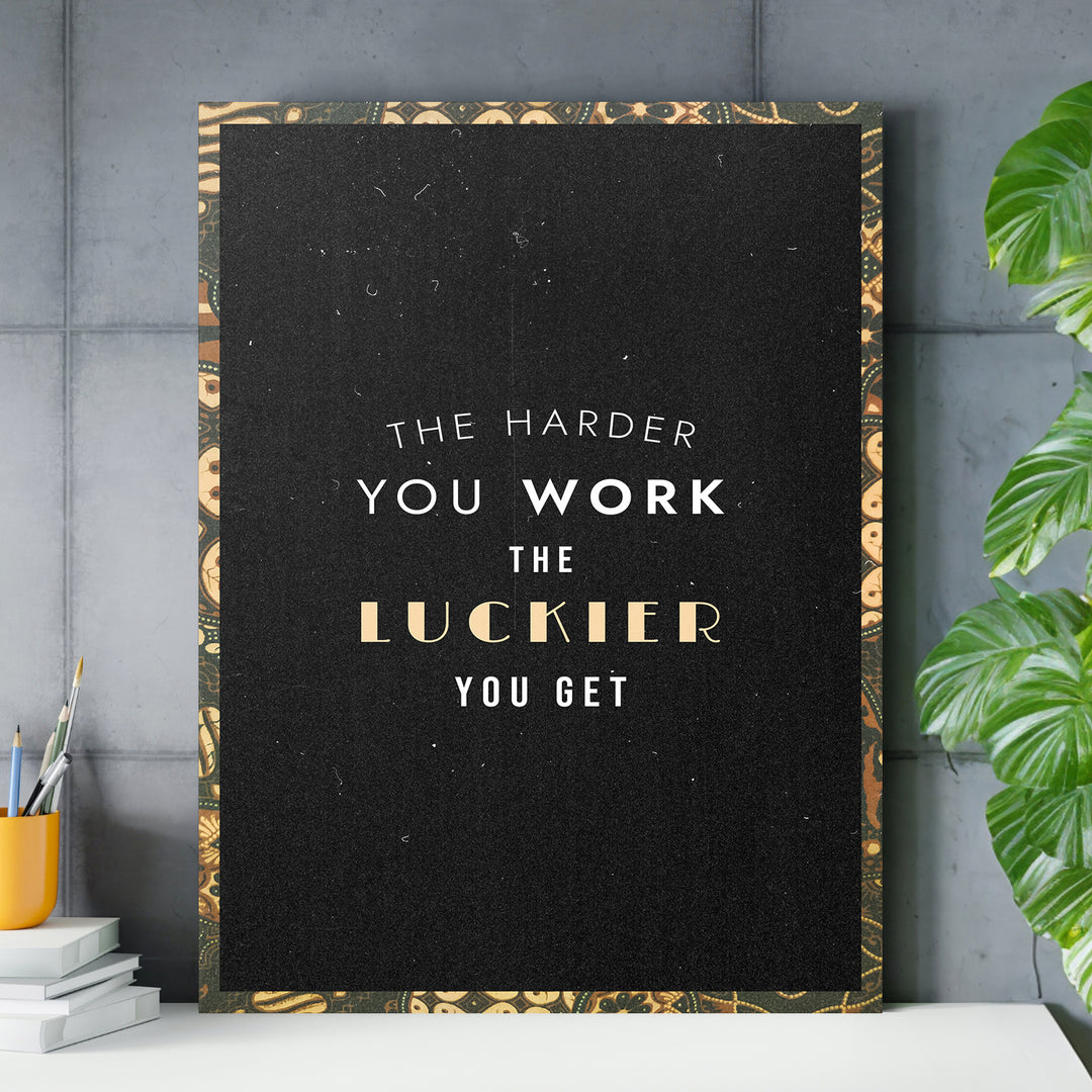 Motivační obraz - The Harder You Work nad pracovním stolem.