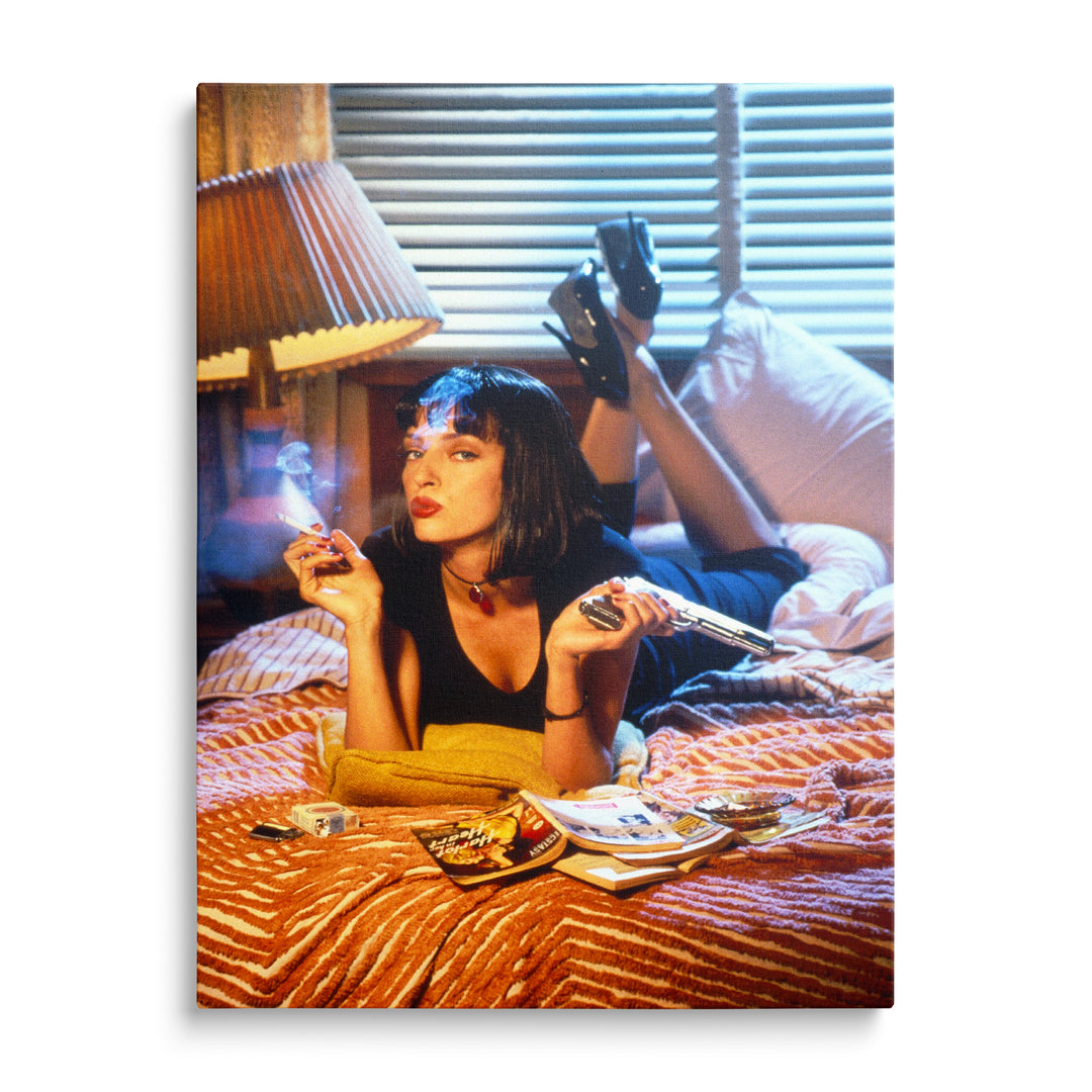 Mia Wallace s tmavou ofinou a cigaretou leží na oranžovočervené pruhované přikrývce, žlutá lampa a modré žaluzie v pozadí.