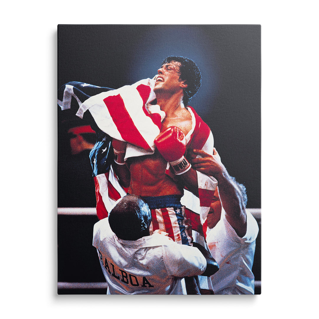 Rocky se zdviženýma rukama a červenými boxerskými rukavicemi, americká vlajka a trenér s nápisem Balboa na tmavém pozadí.