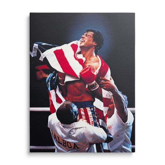 Rocky se zdviženýma rukama a červenými boxerskými rukavicemi, americká vlajka a trenér s nápisem Balboa na tmavém pozadí.