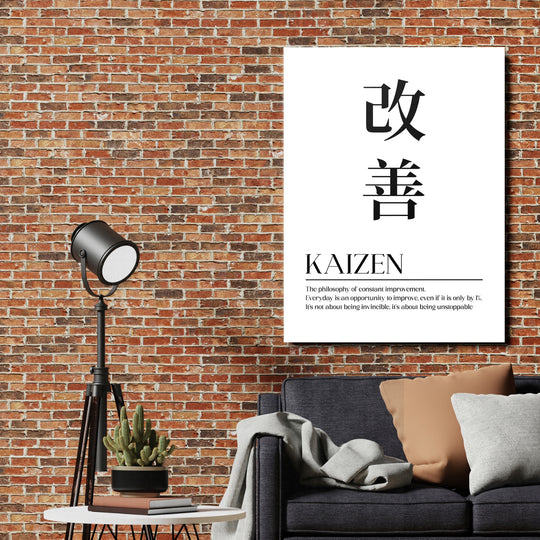 Motivační obraz na plátně Kaizen s japonským citátem na cihlové zdi v obýváku u lampy a pohovky