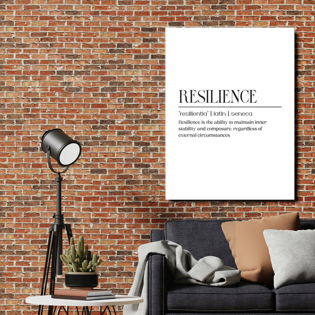 Motivační obraz na plátně s nápisem Resilience nad tmavou pohovkou, industriální lampa a cihlová zeď