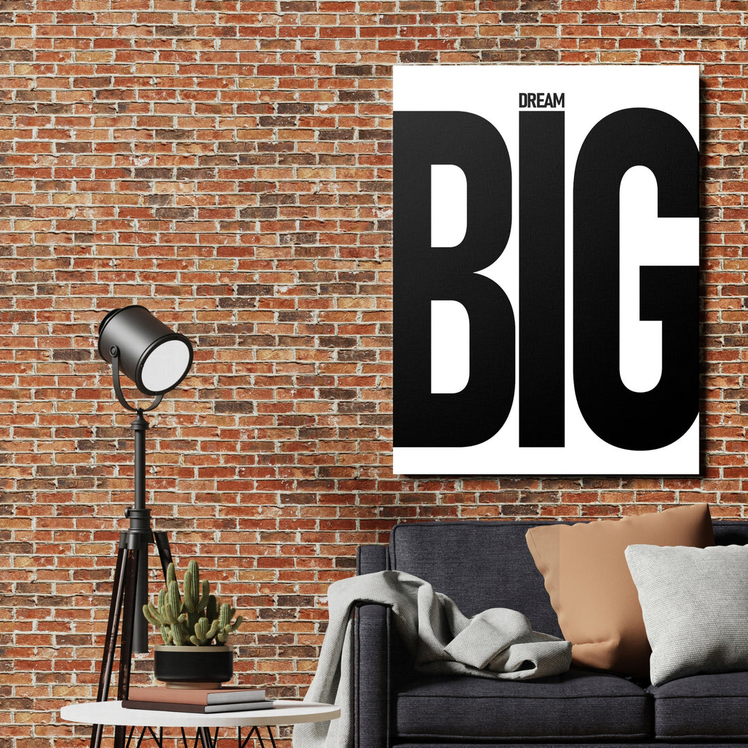 Motivační obraz na plátně s nápisem Dream BIG v industriálním interiéru s cihlovou zdí, lampou a sedačkou