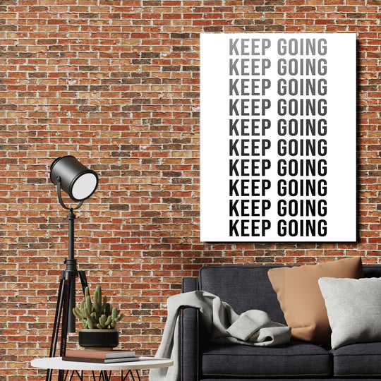 Motivační obraz na zeď s nápisem KEEP GOING, cihlová stěna a pohovka v moderním interiéru