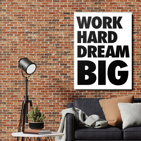 Motivační obraz na plátně WORK HARD DREAM BIG v industriálním interiéru nad tmavě šedou sedačkou