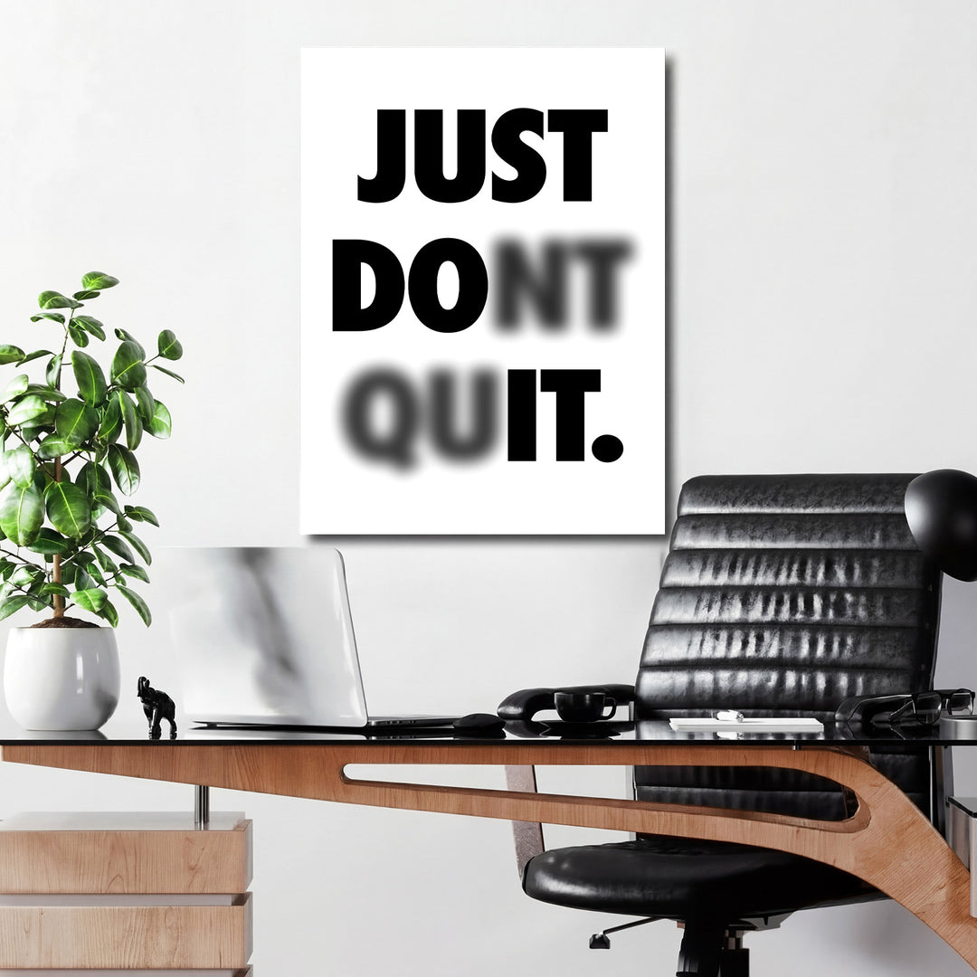 Motivační obraz na plátně s černobílým nápisem Just Don’t Quit nad pracovním stolem v kanceláři