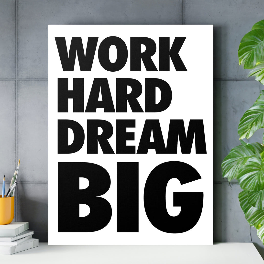 Motivační obraz na plátně WORK HARD DREAM BIG s černým nápisem zavěšený v moderní kanceláři