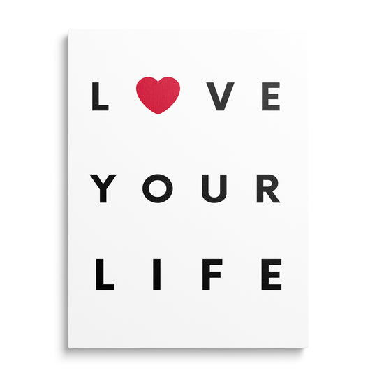 Bílý obraz s černým nápisem Love Your Life a červeným srdcem