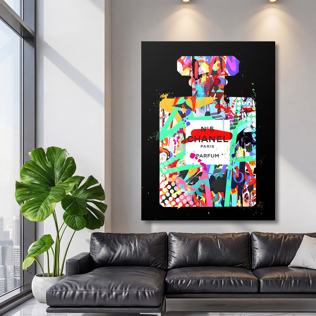 Motivační pop art obraz na zeď Chanel No.5 v loftovém obýváku s černou koženou pohovkou a rostlinou monstera