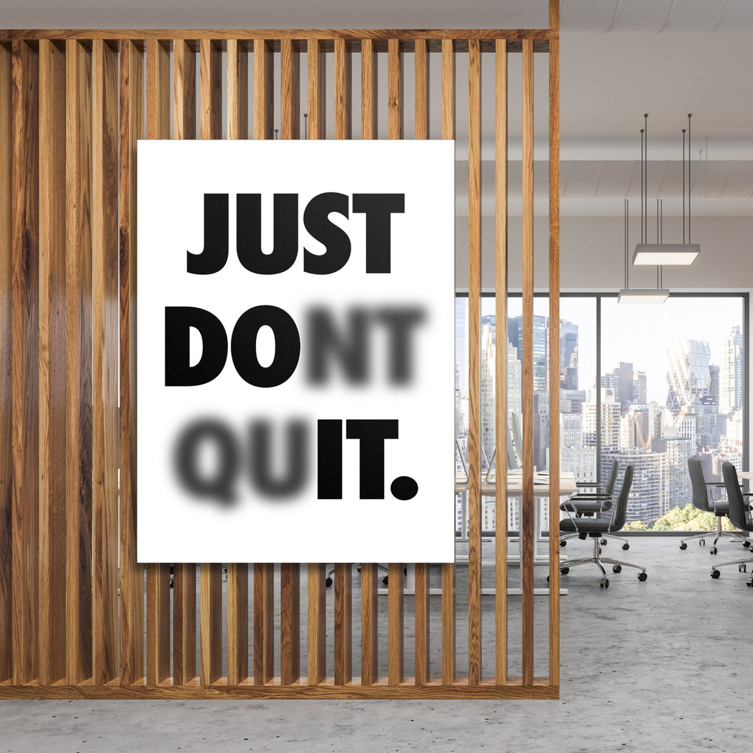 Motivační obraz na plátně s minimalistickým nápisem Just Don't Quit v moderní kanceláři za dřevěnou příčkou