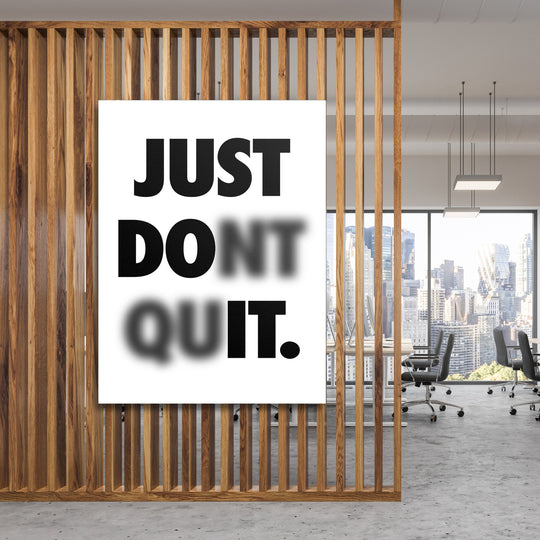 Motivační obraz na plátně s minimalistickým nápisem Just Don't Quit v moderní kanceláři za dřevěnou příčkou