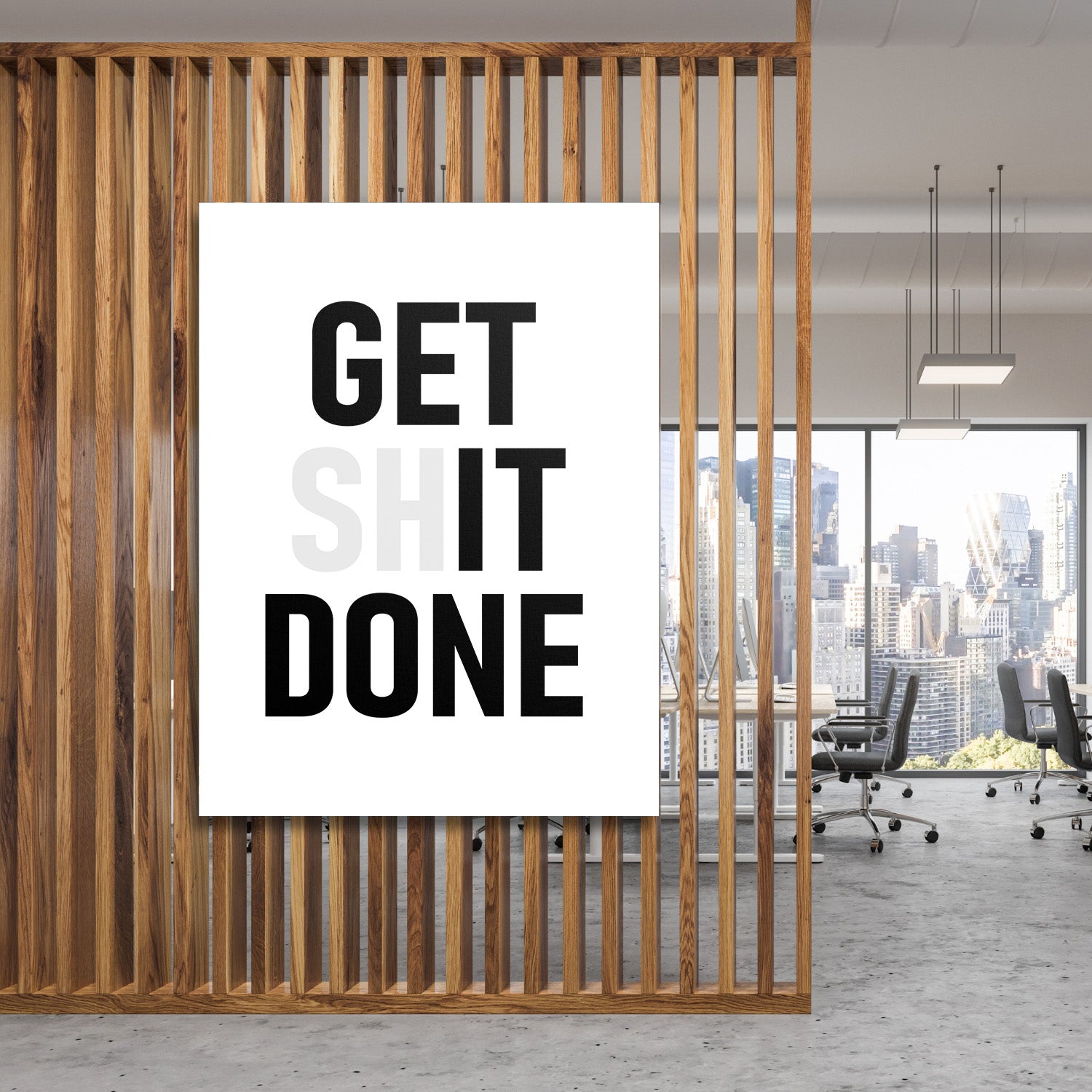 Motivační obraz na plátně s nápisem GET SHIT DONE zavěšený za dřevěnými lamelami v moderní kanceláři