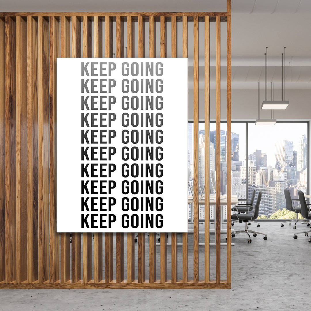 Černobílý motivační obraz na zeď s opakovaným nápisem Keep Going v moderní kanceláři