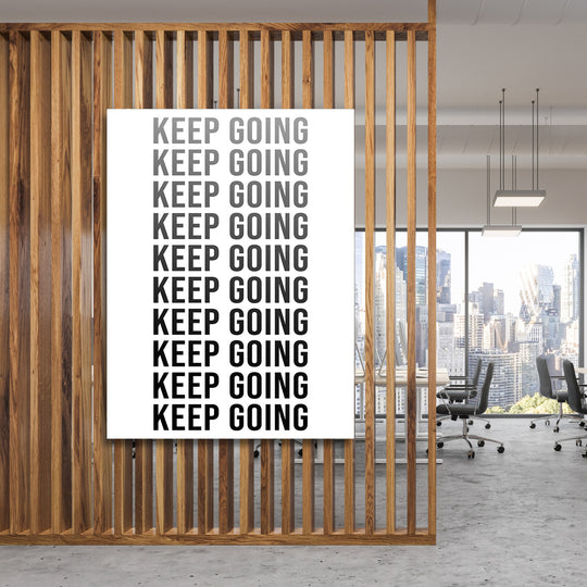 Černobílý motivační obraz na zeď s opakovaným nápisem Keep Going v moderní kanceláři