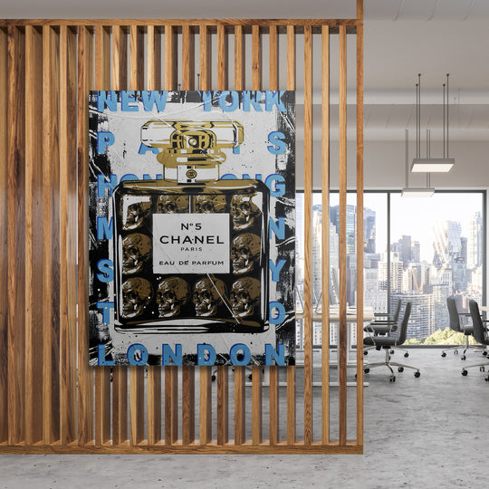 Motivační pop art obraz na plátně s lahví Chanel No.5 a lebkami v moderní kanceláři s výhledem na město