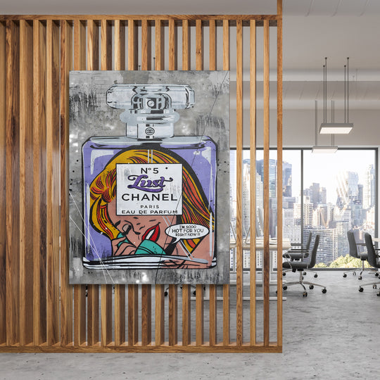 Pop art obraz s parfémem a ženským portrétem, zavěšený na dřevěné příčce v moderní kanceláři