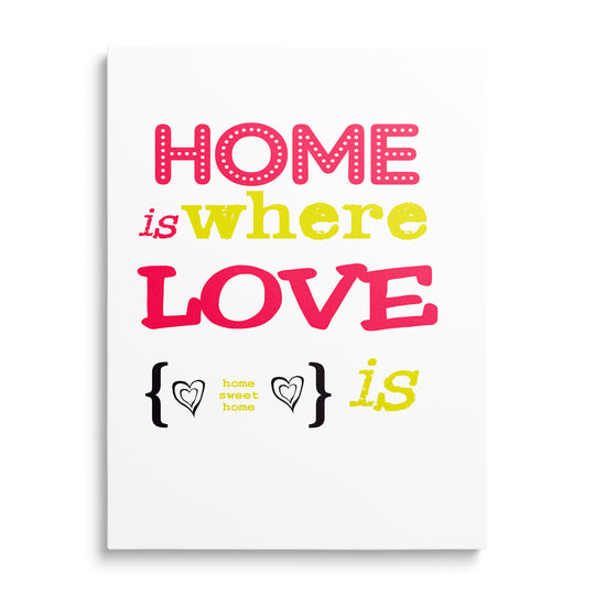 Růžový a žlutý nápis Home Is Where Love Is na bílém pozadí